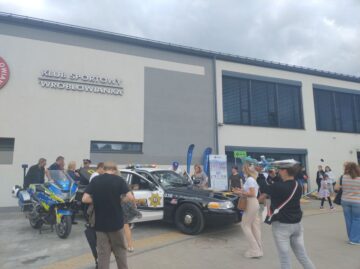 Motocykl policyjny i&nbsp;amerykański radiowóz policyjny przed Klubem Sportowym Wróblowianka