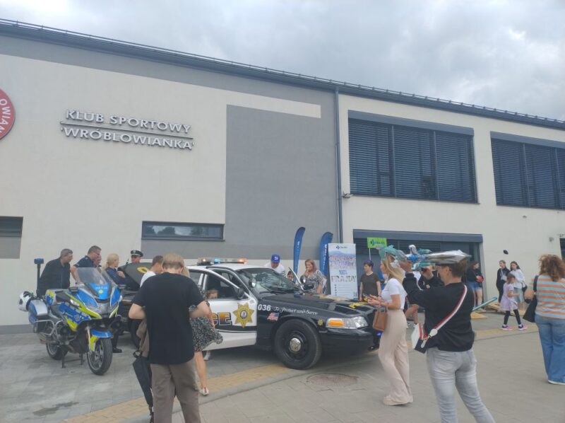 Motocykl policyjny i&nbsp;amerykański radiowóz policyjny przed Klubem Sportowym Wróblowianka